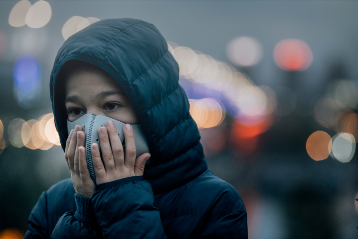 Woman touching her face mask in an urban setting.