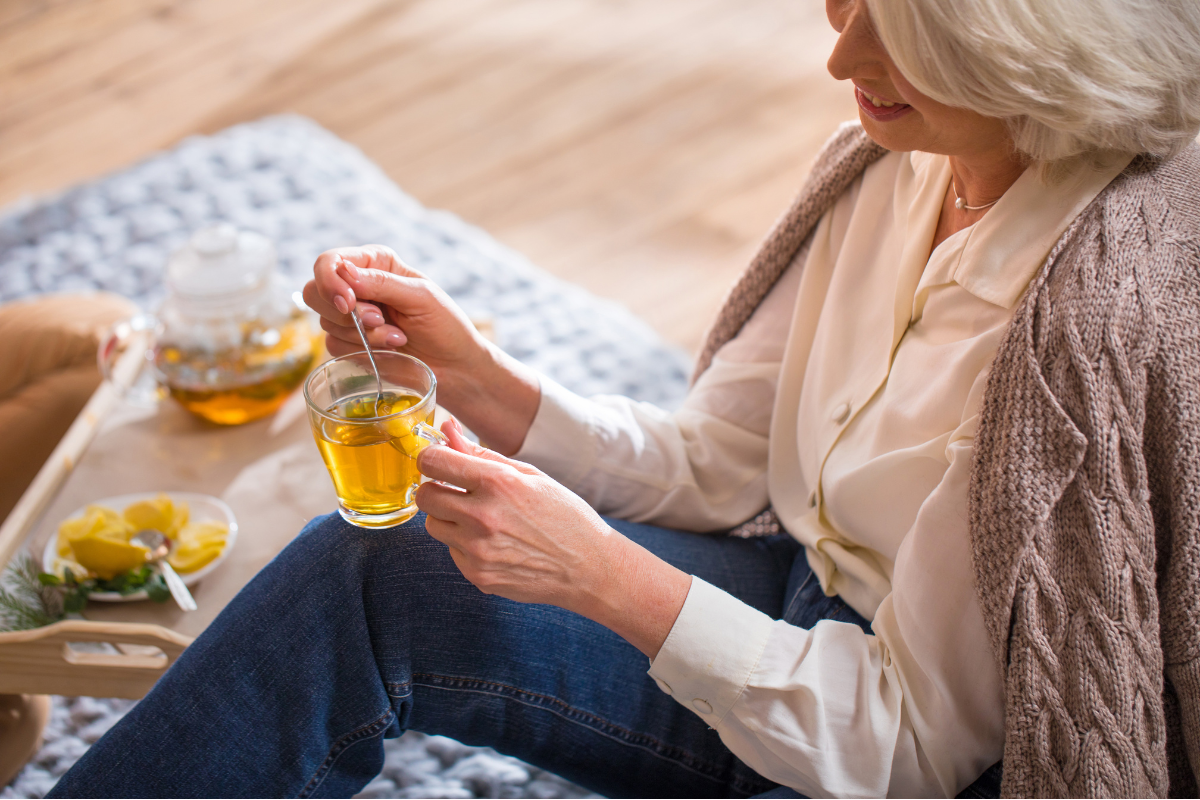 Old smiling woman with a cup of tea in her hand.
