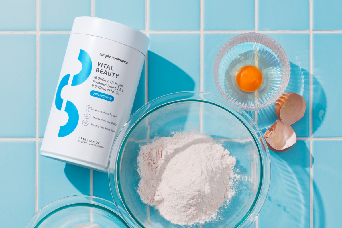 Simply Nootropics Vital Beauty collagen powder with baking ingredients on a blue tiled surface.