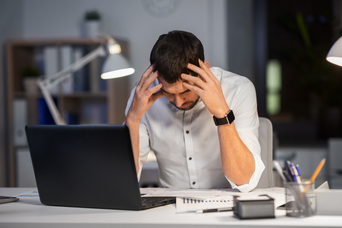 Man sitting at a desk late at night, holding his head in frustration.