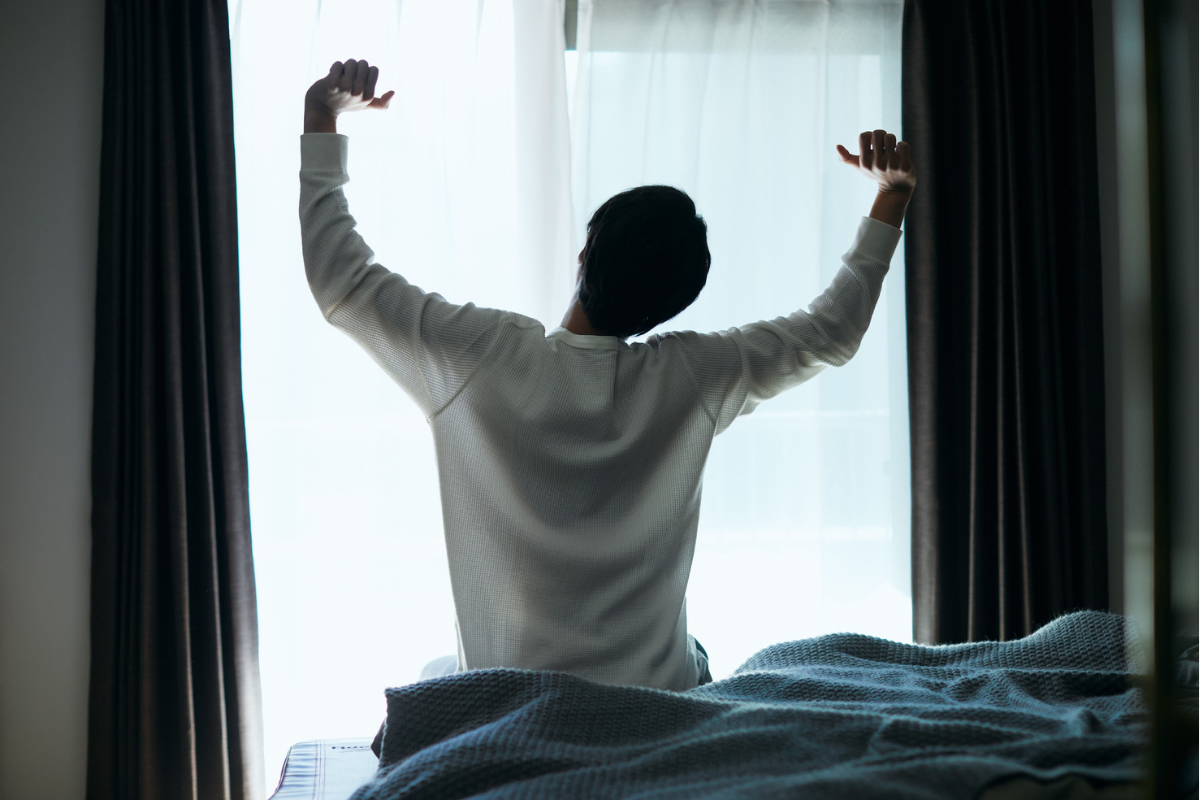 Person stretching by a window after waking up.