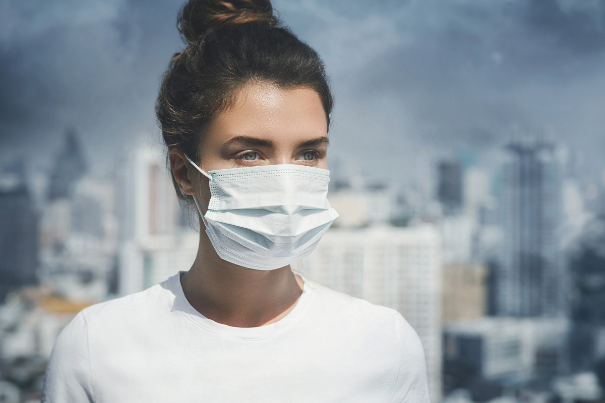 Woman wearing a protective face mask in a polluted city.
