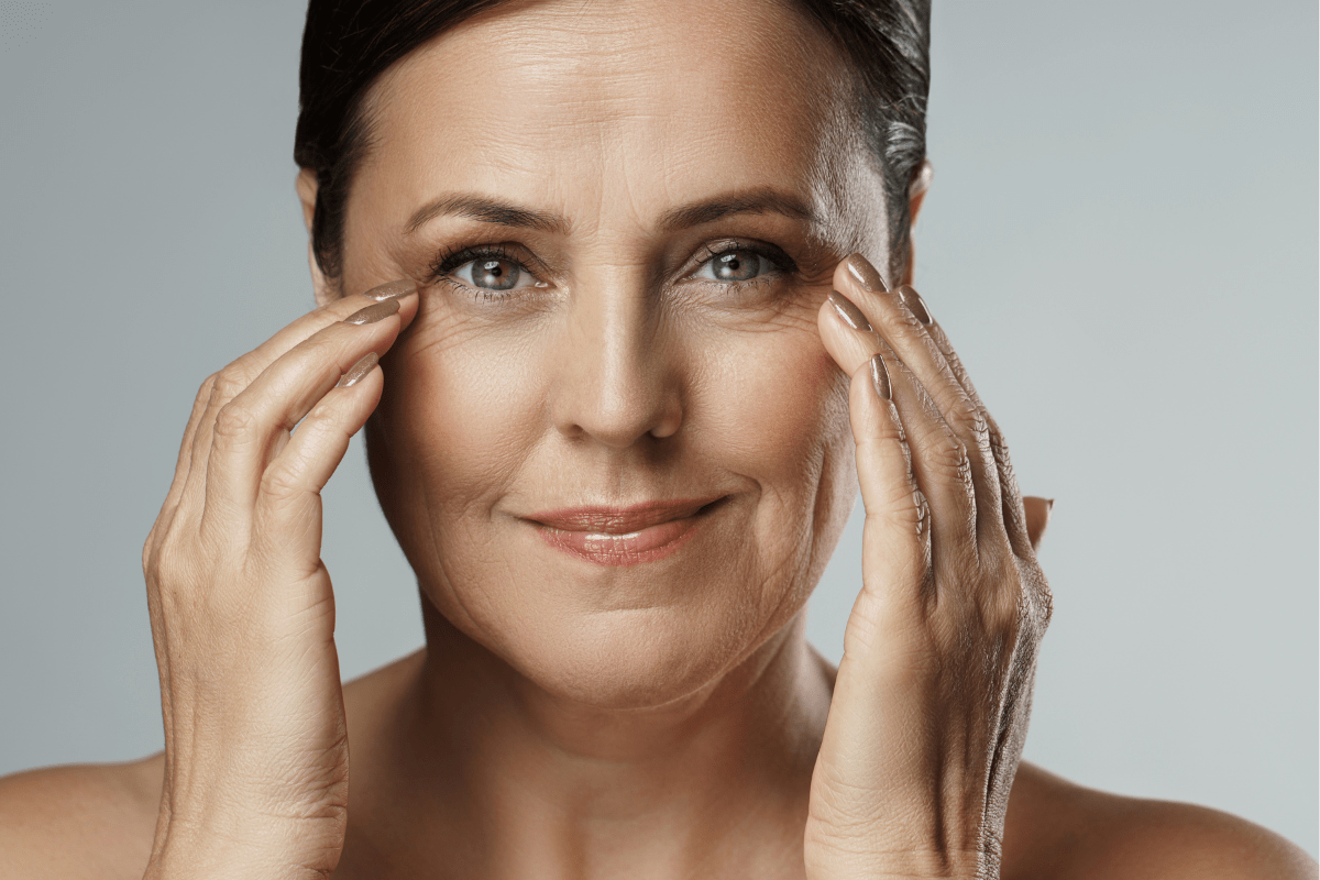 Close-up of a woman touching her face, showcasing smooth skin and minimal wrinkles.