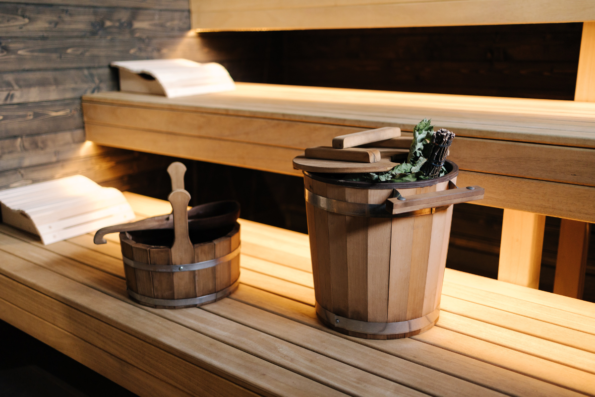 Wooden sauna interior with buckets and ladle on bench.