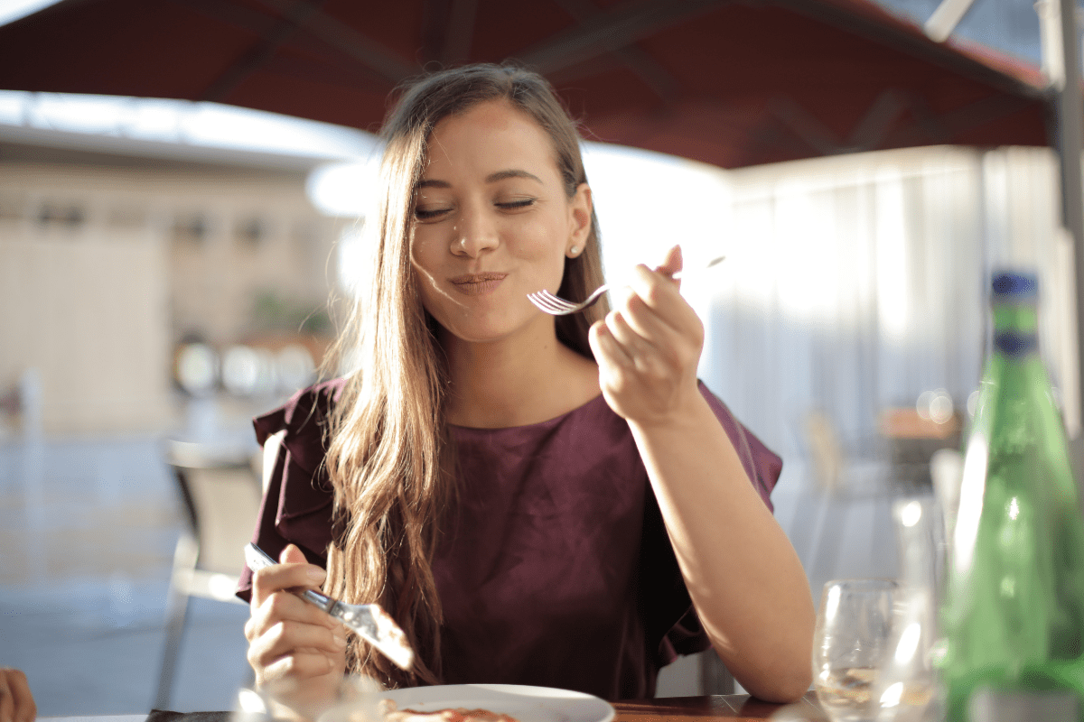 Woman enjoying a meal at an outdoor restaurant.