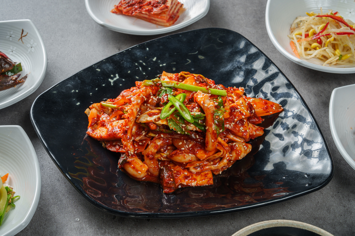 Plate of spicy fermented kimchi garnished with green chili and sesame seeds.