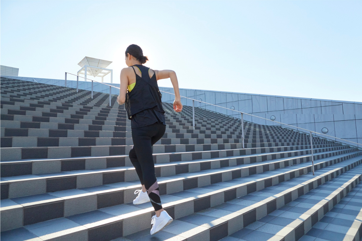 Woman running up outdoor stairs during a workout.