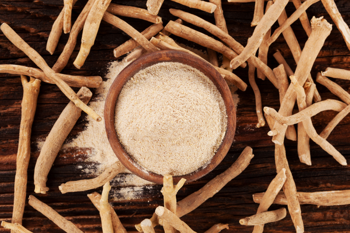 Ashwagandha roots with powdered extract in a wooden bowl.