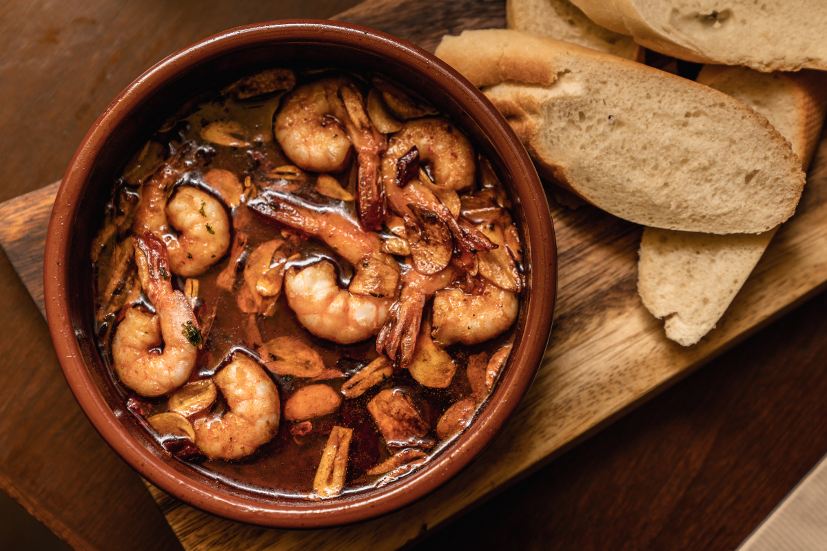 Garlic shrimp served in a dish with sliced bread.