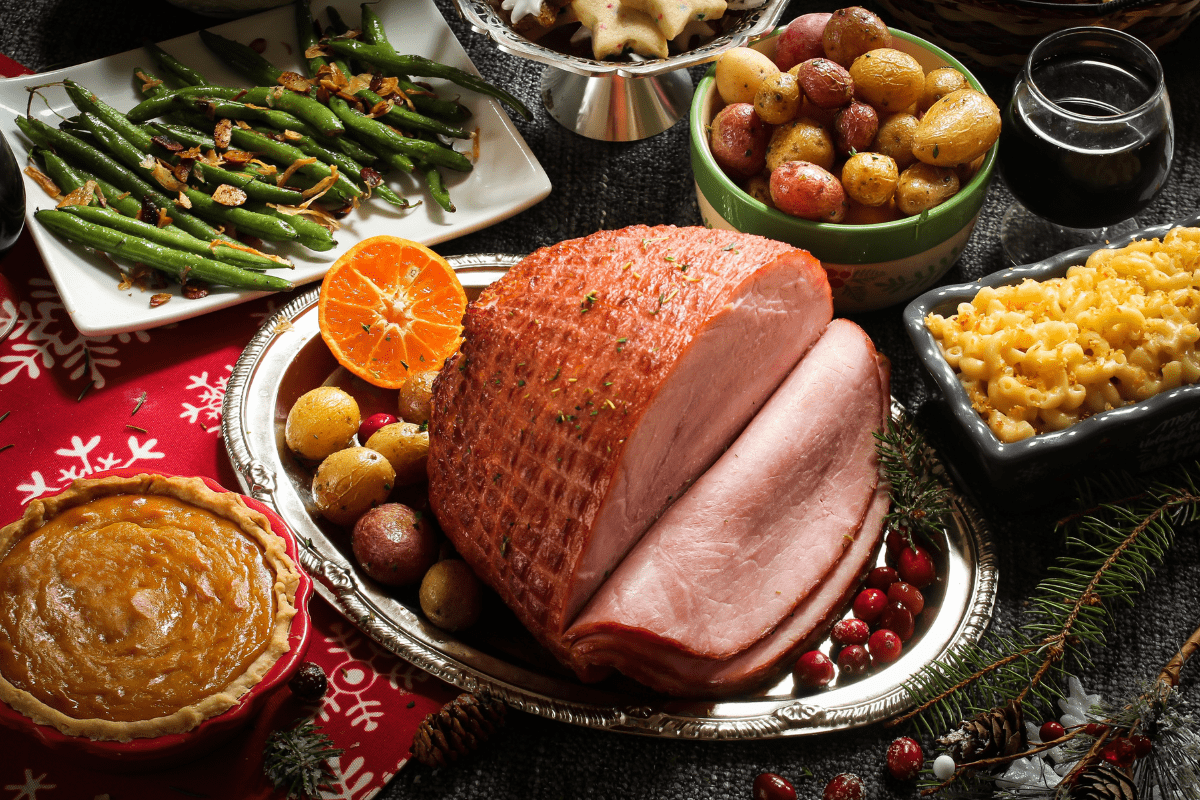 A festive holiday meal featuring glazed ham on a decorated table.