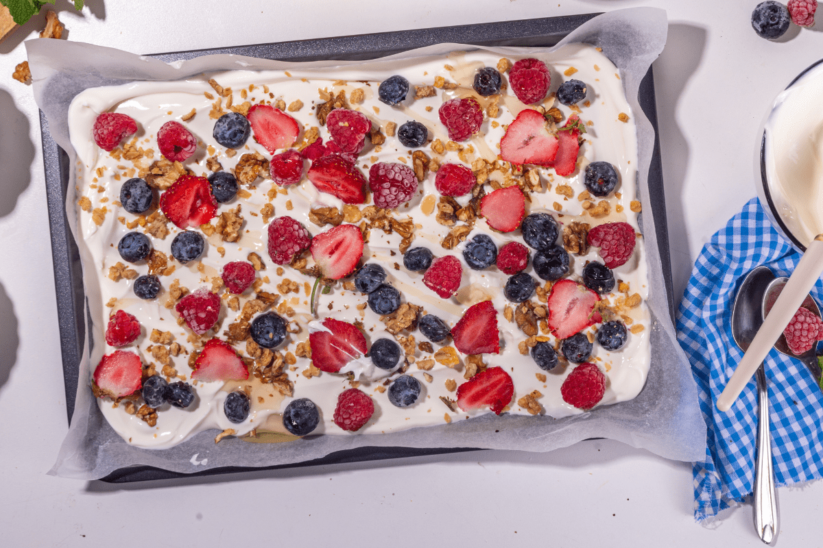 Tray of frozen yoghurt bark topped with berries and granola.