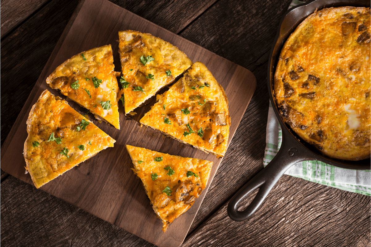 A freshly baked garlic mushroom frittata, sliced and garnished with herbs.