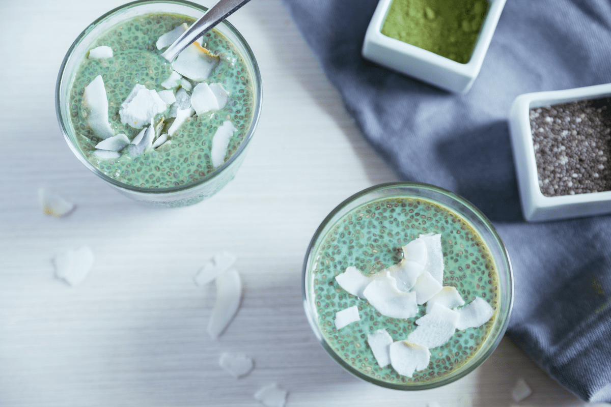 Glasses of matcha chia pudding topped with coconut flakes.